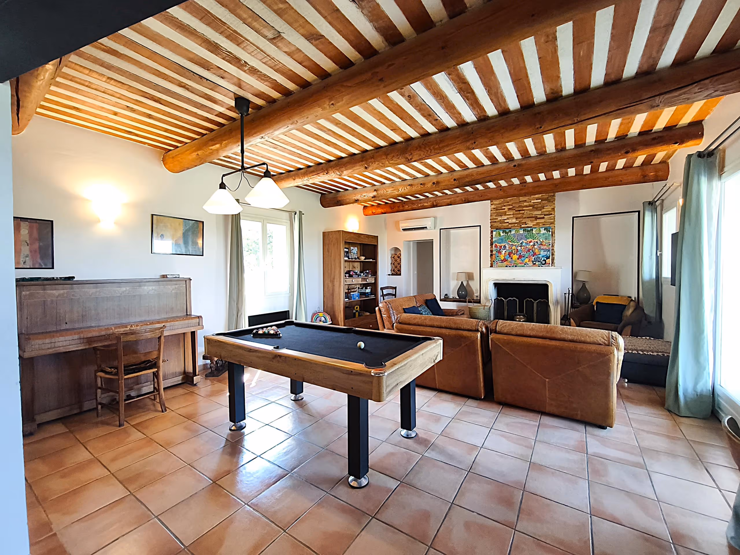 Le salon de la Villa Roucas avec son billard et son plafond à poutres apparentes