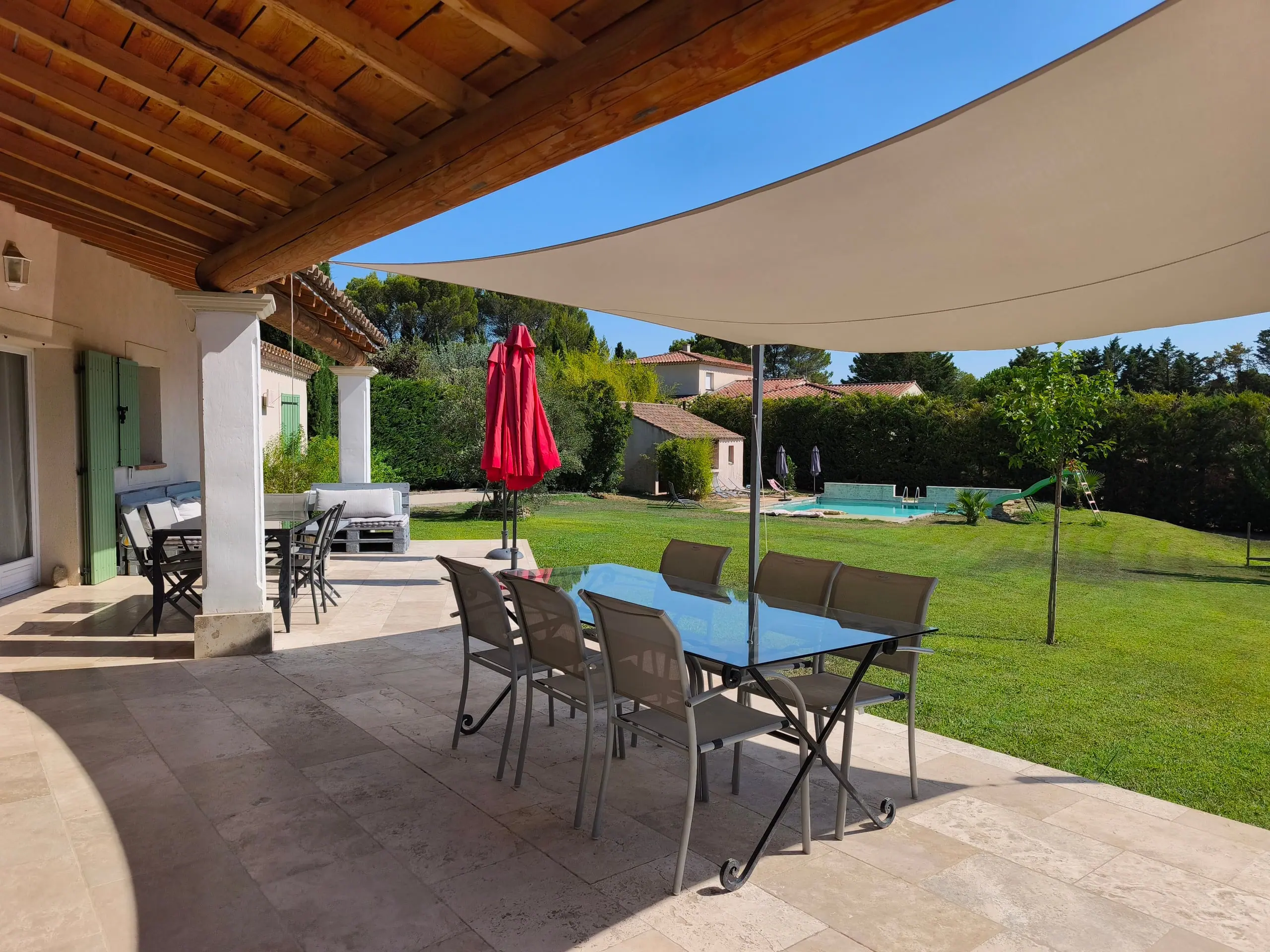 La terrasse en pierre sous sa charpente à poutres