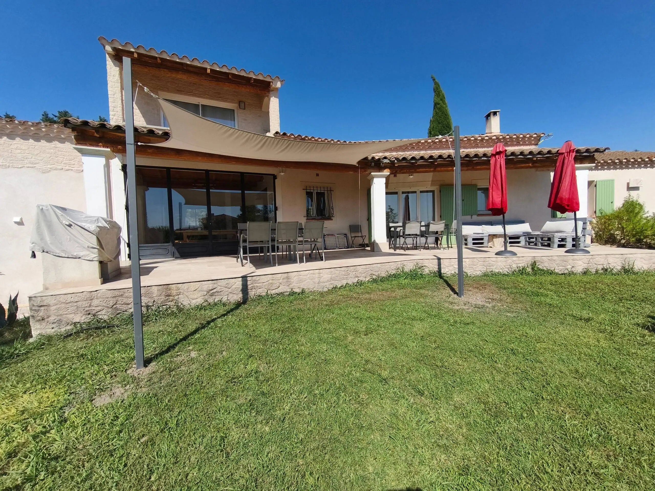 La pelouse du jardin et la terrasse couverte de la villa
